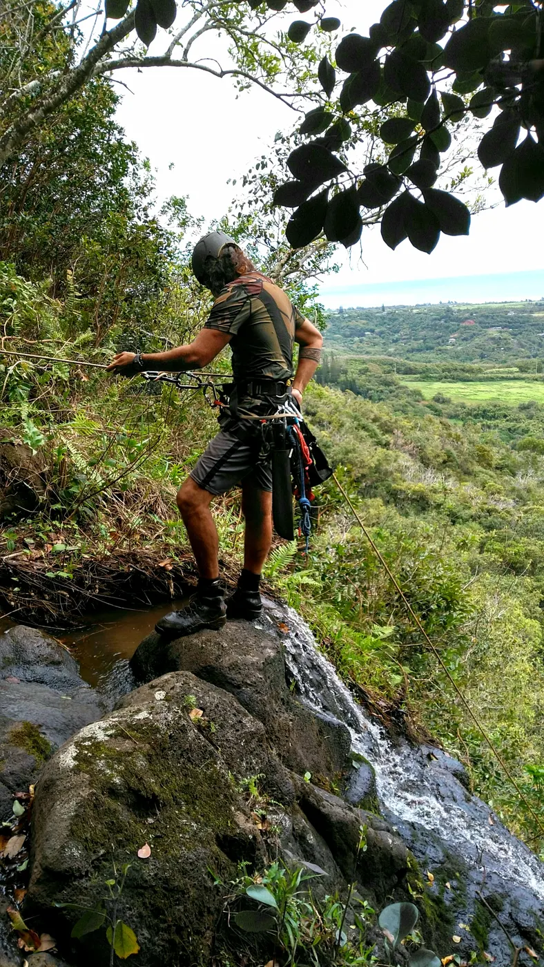 Renan Gobbet Hernandez in a helmet and harness at the top of a waterfall